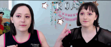 two women are standing in front of a sign that says roa
