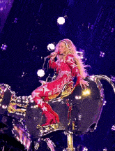 a woman in a red jumpsuit is singing into a microphone while sitting on a drum .