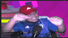 a man wearing a blue shirt and a red hat is standing in front of a microphone