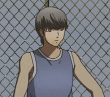 a man in a blue tank top is standing next to a chain link fence .