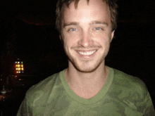 a man with a beard wearing a green shirt smiles