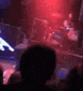 a group of people are watching a band perform on stage in a dark room .
