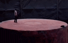 a man in a white shirt is standing in a circle with his arms up