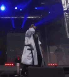 a man in a white robe is singing into a microphone on stage .