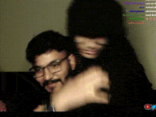 a man with glasses and a woman with long black hair are hugging each other .