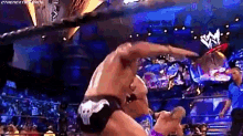 two men are wrestling in a wrestling ring and one of them is wearing skull shorts .