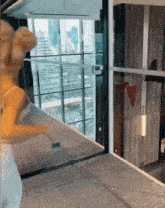 a woman in a white dress is standing in a room with lots of windows