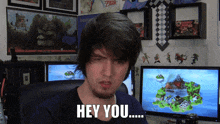 a man sitting in front of two computer monitors with the words hey you written on his face