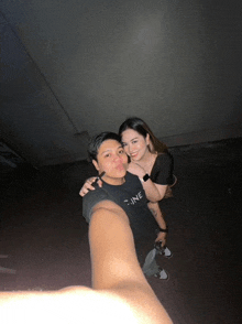 a man wearing a black shirt that says " fine " is taking a selfie with a woman
