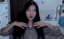 a woman with long black hair is wearing a shirt with a pattern of flowers