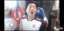 a man is sitting in a chair with his mouth open and a fan behind him .