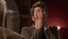 a man in a suit and tie is making a surprised face in front of a mirror
