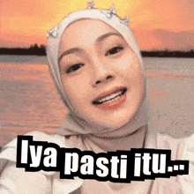 a woman wearing a hijab is smiling with the words " iya pasti itu " above her