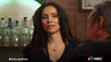 a woman is talking to a man in a bar with the hashtag #chicagofire on the bottom
