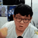 a man wearing glasses and a white shirt is talking into a microphone