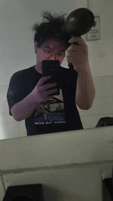 a man taking a selfie in front of a mirror wearing a shirt that says " bad shit " on it
