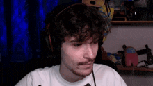 a man with curly hair and a beard is wearing headphones and a microphone while sitting in a chair .