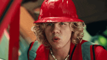 a man wearing a red hard hat and pearls necklace