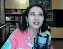a woman wearing ear buds is talking into a microphone .