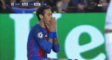a soccer player is kneeling in front of a green sign that says heineken