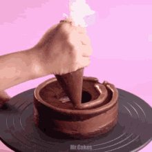 a person is frosting a chocolate cake with a piping bag ..