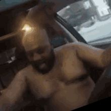 a shirtless man with a beard is sitting in the passenger seat of a car .