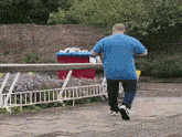 a man in a blue shirt is walking across a sidewalk