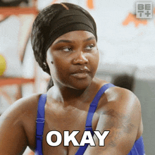 a woman in a blue sports bra says okay on her face