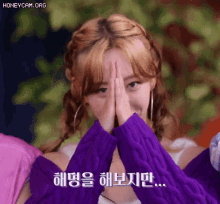 a woman in a purple sweater is covering her face