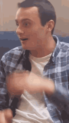 a young man in a plaid shirt is sitting on a blue couch