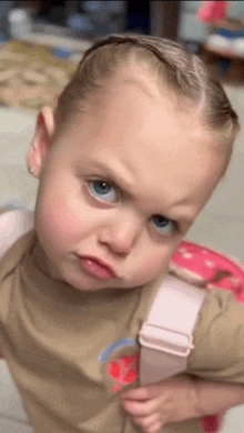 a little girl wearing a brown shirt and a pink backpack making a funny face