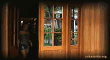a woman is standing in a doorway with the website sakamoke.org written on the bottom
