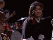 a woman in a plaid skirt is sitting in a dark room with other people