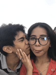a man kisses a woman on the cheek while she makes a funny face