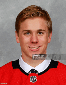 a young man wearing a nhl jersey and tie smiles for the camera