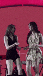 two women are dancing on a stage with a nord electro keyboard behind them