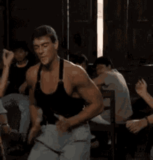 a man without a shirt is dancing in a room with people .
