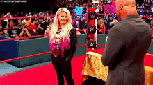 a woman is standing on a red carpet in a wrestling ring talking to a man .