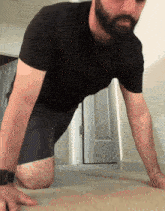 a man in a black shirt and blue shorts is doing push ups on the floor