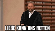 a man in a judge 's robe is standing in front of a wooden blind and laughing .