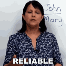 a woman stands in front of a white board with the name john mary written on it