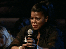 a woman is crying while holding a microphone with the letter x on it