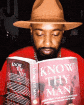 a man in a hat is reading a book called know thy man