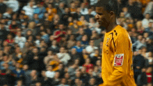 a soccer player wearing a yellow jersey with a coca cola logo on his sleeve