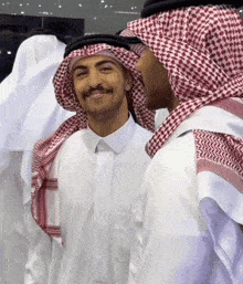 a man wearing a white shirt and a red and white checkered head scarf