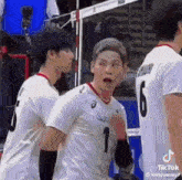 two volleyball players are standing next to each other on a court .