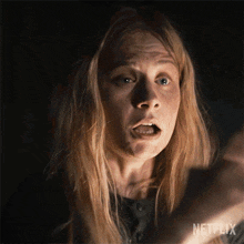 a close up of a woman 's face in a dark room with a netflix logo in the corner .
