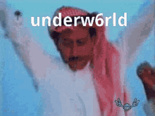 a man with his arms outstretched is wearing a red head scarf and a hat with the word underworld written on it .