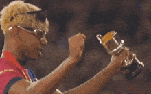 a man wearing sunglasses is holding a trophy in his hands