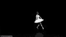a black and white photo of a ballerina in a white tutu dancing on a stage .